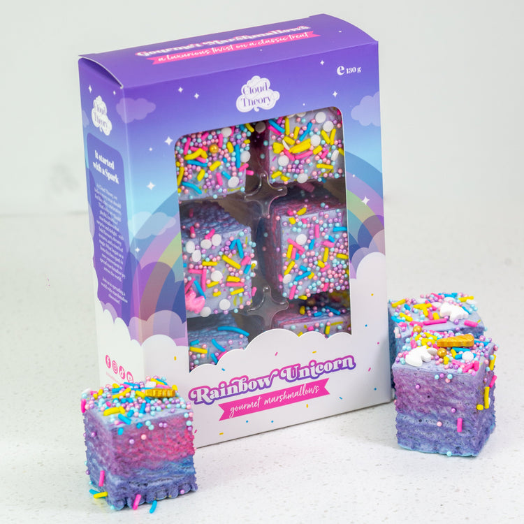 Colorful unicorn-themed product packaging with two stacks of similar products on a white background