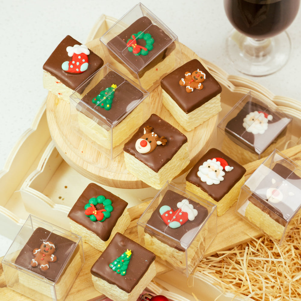 Decorative chocolate treats with Christmas-themed decorations on a wooden stand, accompanied by a glass of red wine.