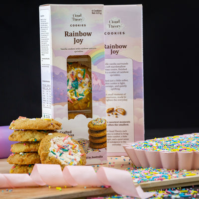 Cookie packaging with cookies and sprinkles on a wooden board against a black background