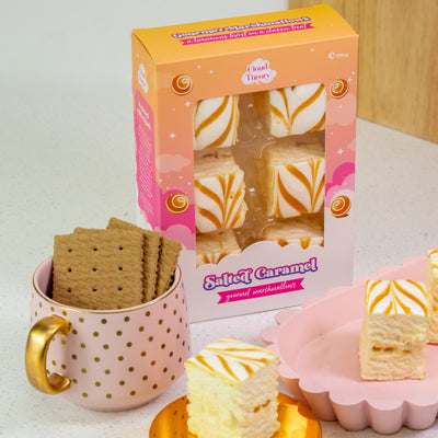 Sweet caramel cookies with packaging, a mug, and a heart-shaped dish on a light surface.
